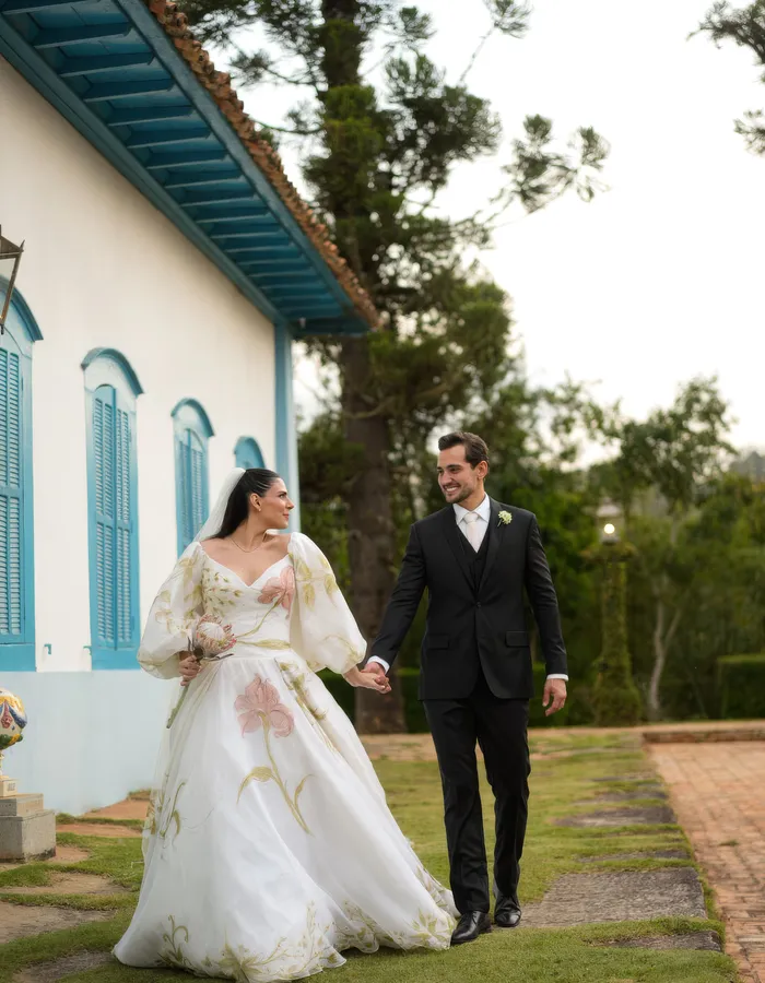 Noivos caminham de mãos dadas em frente ao casarão histórico da Fazenda Fortaleza